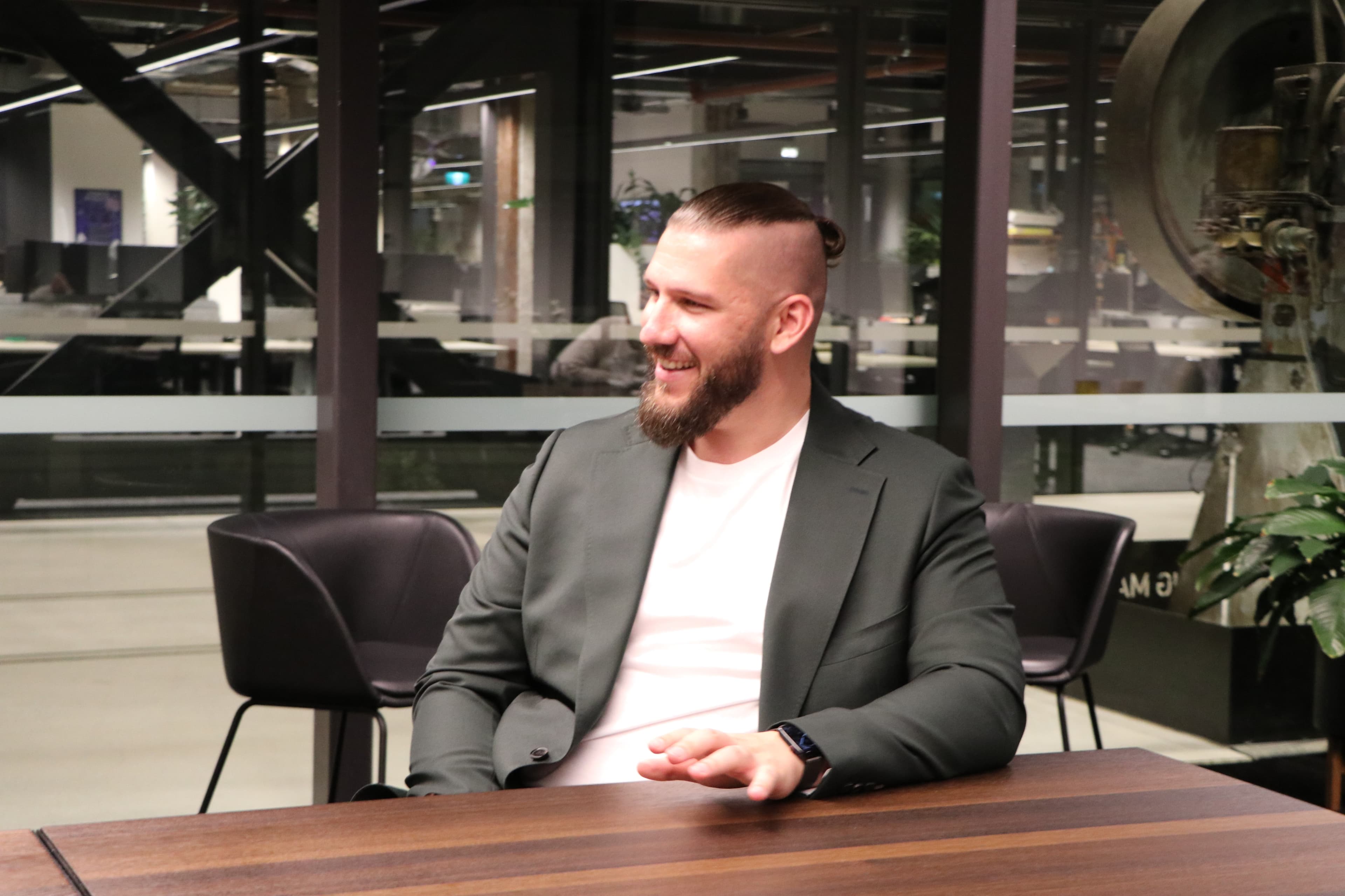Daniel at a workbench-style table in a modern co-working space.
